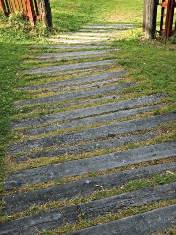 Horisontella linjer skapar en upplevelse av ökad bredd. Något så enkelt som långsmala trampbrädor i gräsmattan kan bidra till att trädgårdsrummet känns bredare. Bild från Träslottet i Arbrå, Hälsingland.