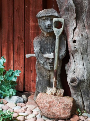 Det var Tittes svärfar från Karelen som tillverkade gubben invid bagarstugan. Spaden i stenen står Titte för. Installationen kallar hon Perkele, ett av de få finska ord som de flesta svenskar kan.