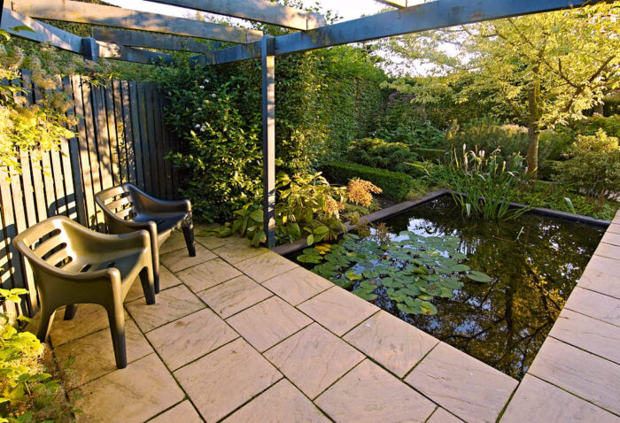 Svarta, tufft designade plaststolar runt fyrkantig trädgårdsdamm