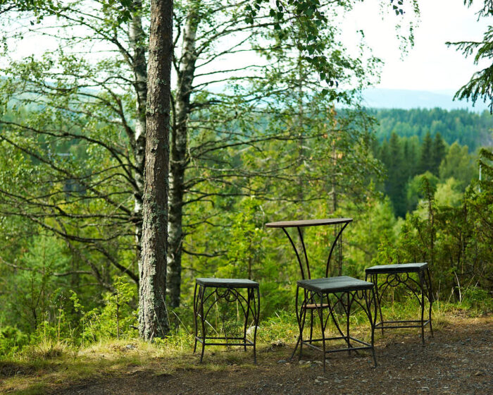 Enkla metallmöbler uppställda i skogskanten på Villa Fraxinus i Ångermanland just där utsikten är som bäst.