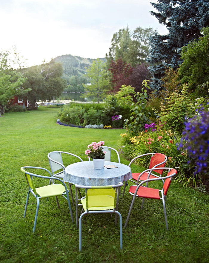 Klassiska trädgårdsmöbler av sammanfogade metallrör med sittytor i färgglad, vävd plast