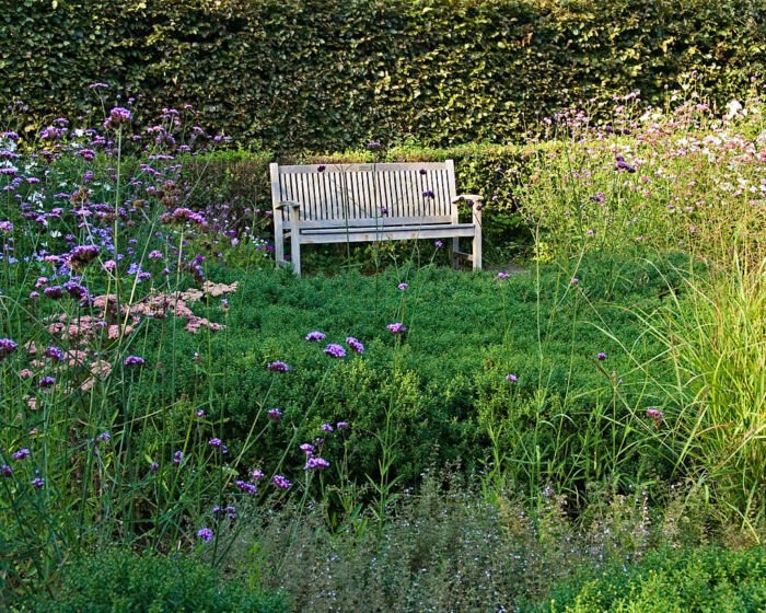 En soffa i hårdträ med en skyddande häck i ryggen