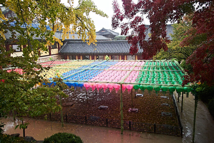 Tempelgård med färggranna bönelanternor i grönt, rosa, blått och gult som bildar tak.