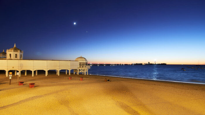 Sen solnedgång över La Caleta i Cádiz med Castillo de San Sebastián i bakgrunden.